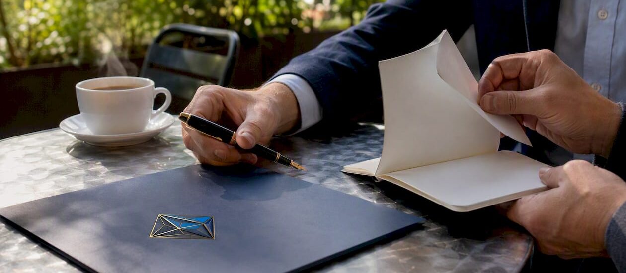 Hands arranging folders and pens with Blue Prysm logo