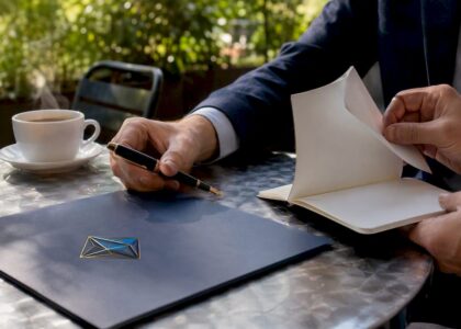 Hands arranging folders and pens with Blue Prysm logo