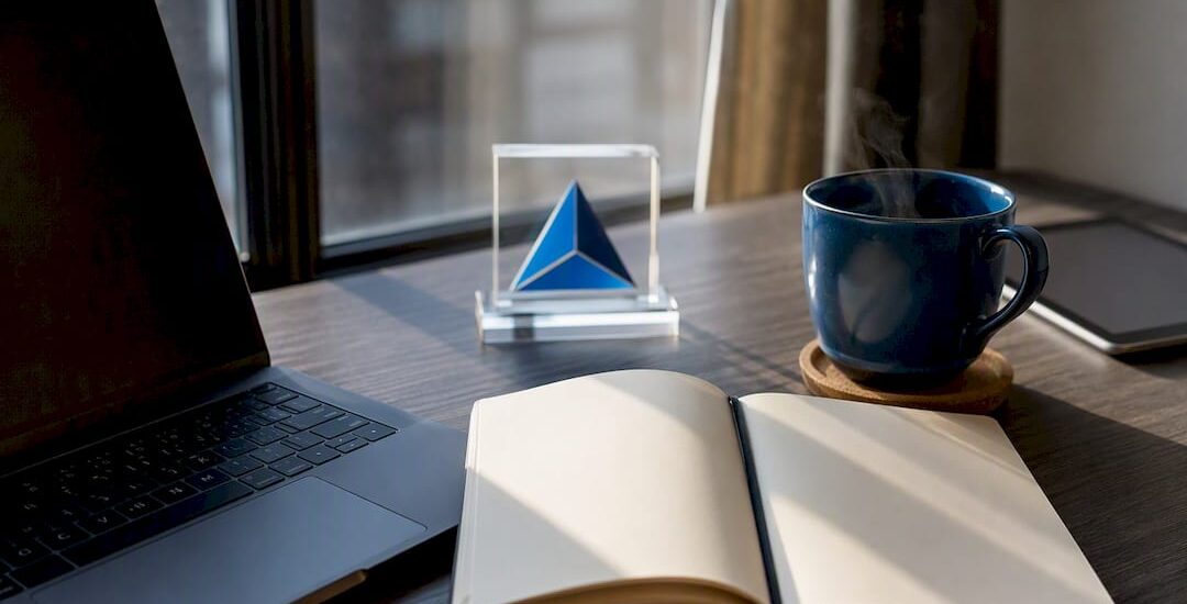Workspace with laptop, coffee, and Blue Prysm logo