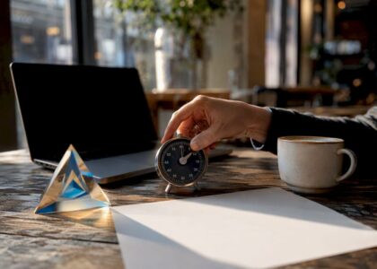 Hand adjusting timer beside Blue Prysm prism on desk