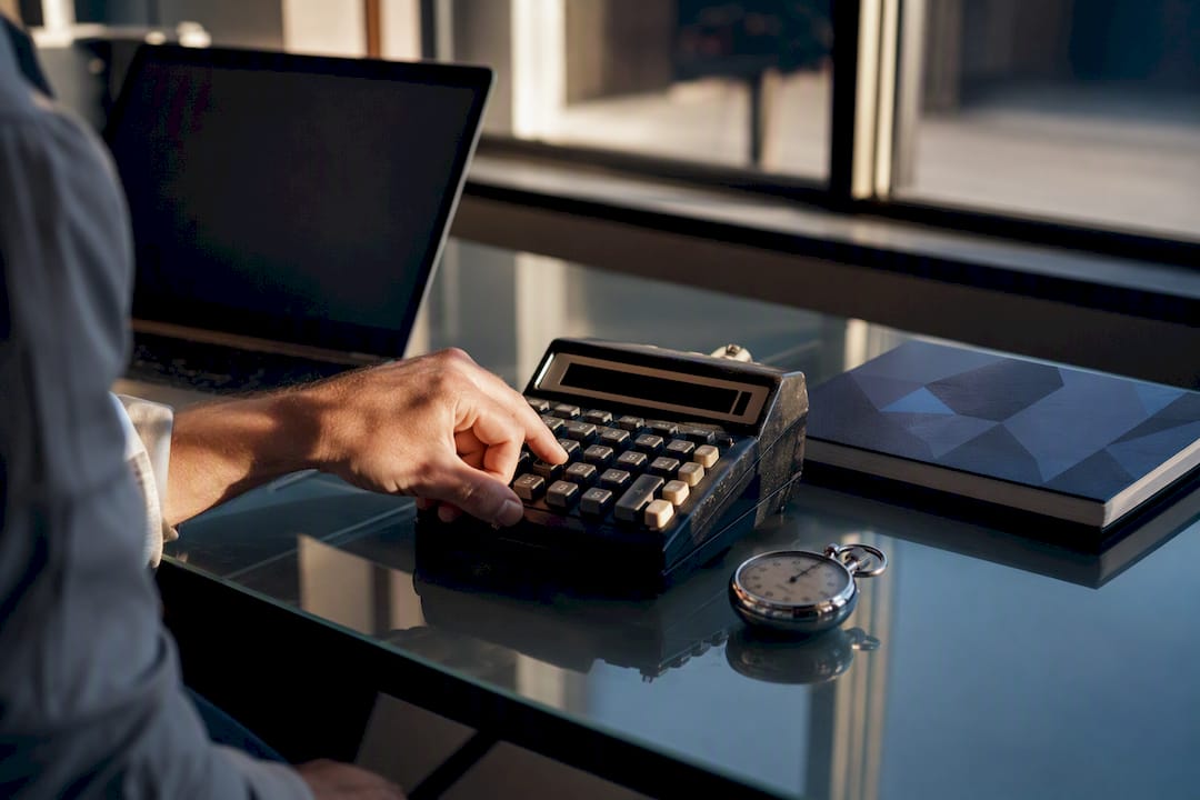 Hand using calculator and stopwatch on desk